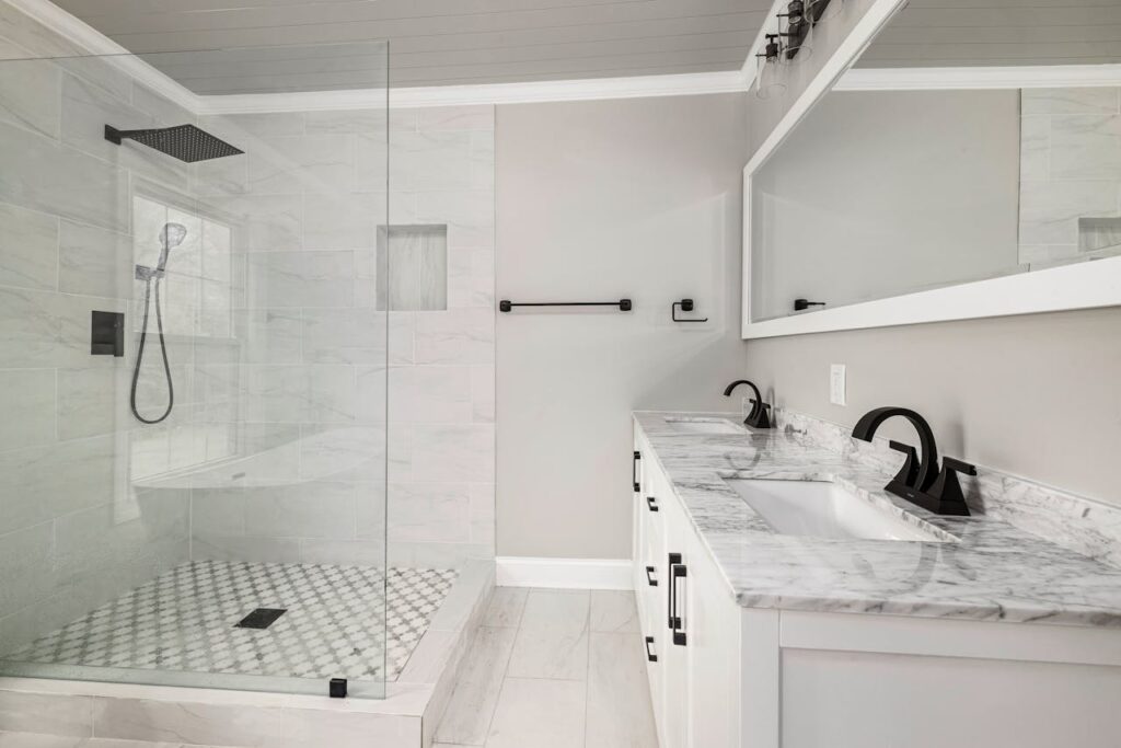 Black and white bathroom with walk-in shower screen on the left and a double vanity on the right with an eye-level mirror