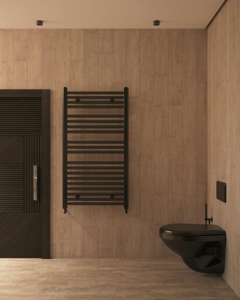 An image of a bathroom with natural wood floor and wall panelling, fitted with black accents, toilet, and door.