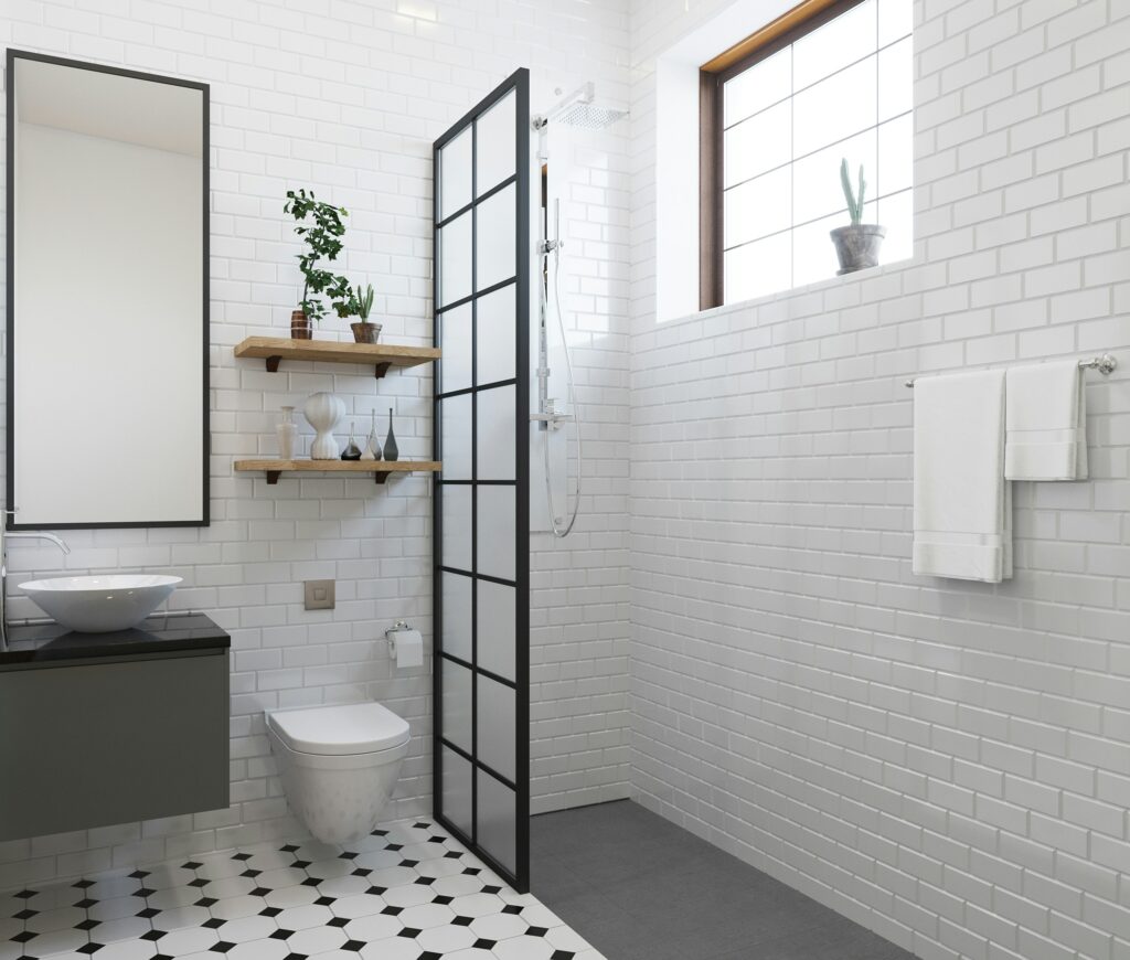 a white subway-tiled bathroom with a walk-in shower, black framed mirror, and black and white geometric flooring