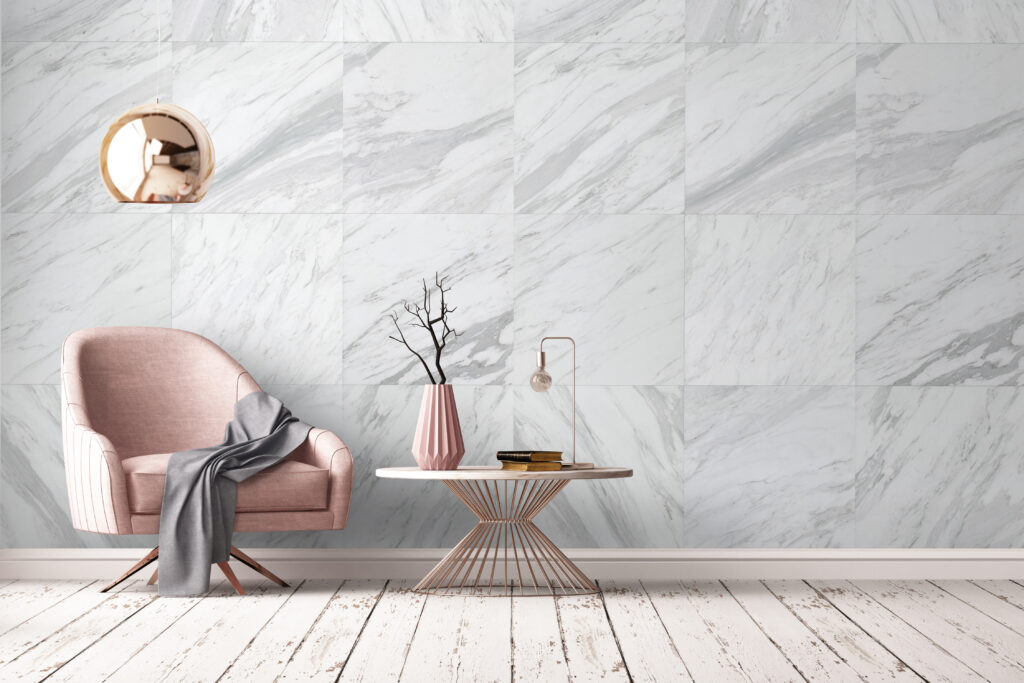 Minimalist living area with a plush, dusty pink armchair, a rose gold side table and lamp, against a large-format white marble feature wall.