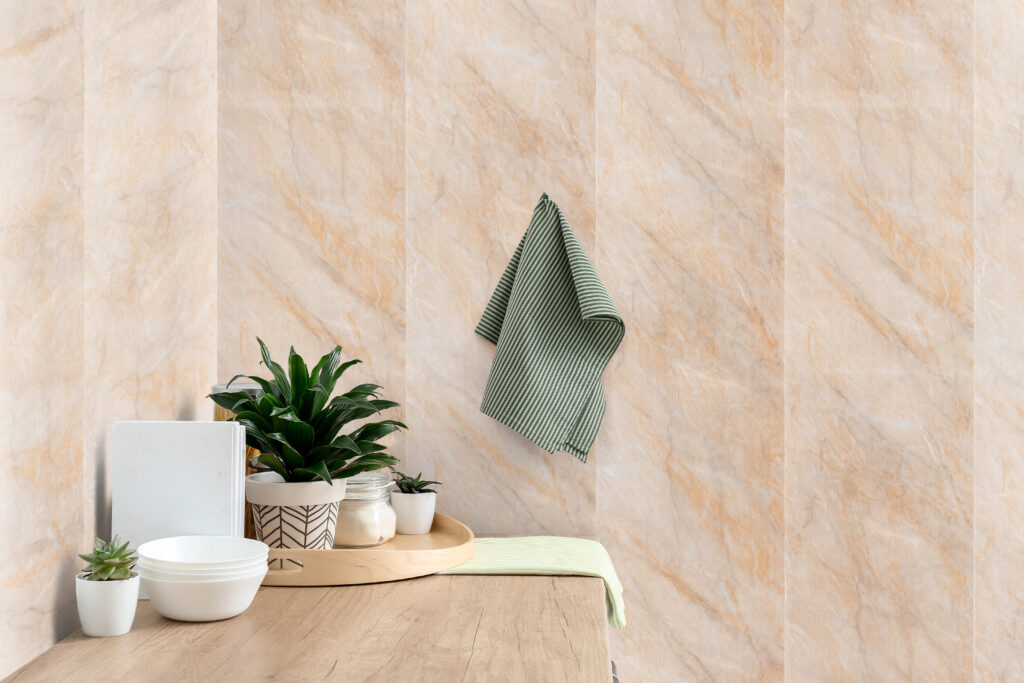 A beige marble bathroom corner featuring a wooden table, potted plants and a striped hand towel on the wall.