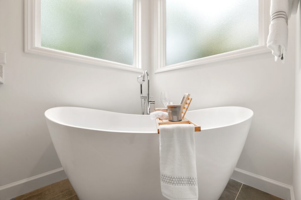 A white freestanding bath underneath a window.
