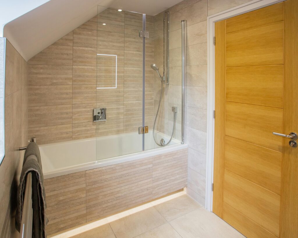 A neutral bathroom with a slat panelled feature wall and matching panelled shower bath.